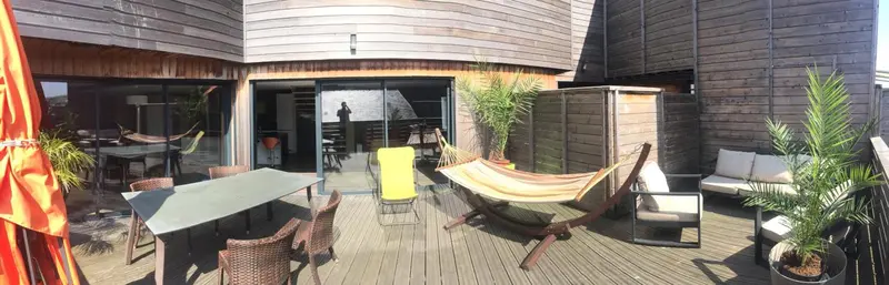 Terrasse aménagée avec mobilier de jardin et hamac.