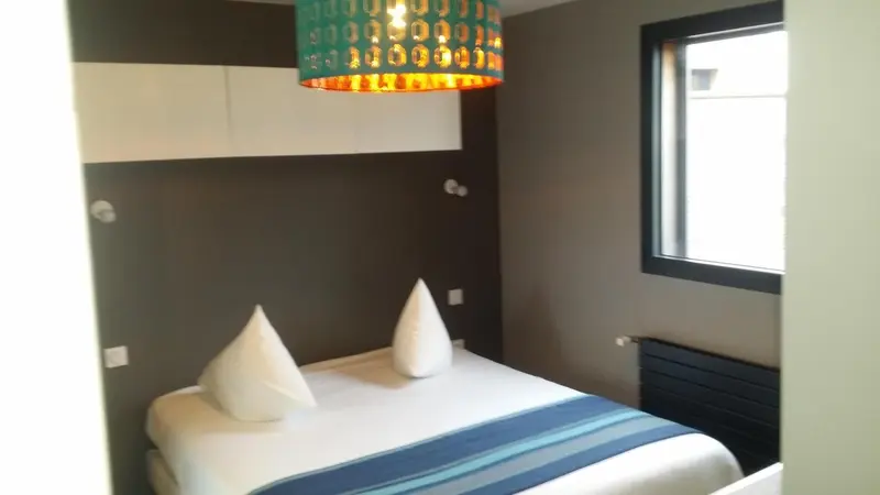 Une chambre moderne avec un lit simple et un éclairage original.
