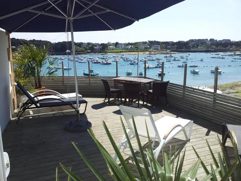 Terrasse en bois avec mobilier de jardin donnant sur un port de plaisance.