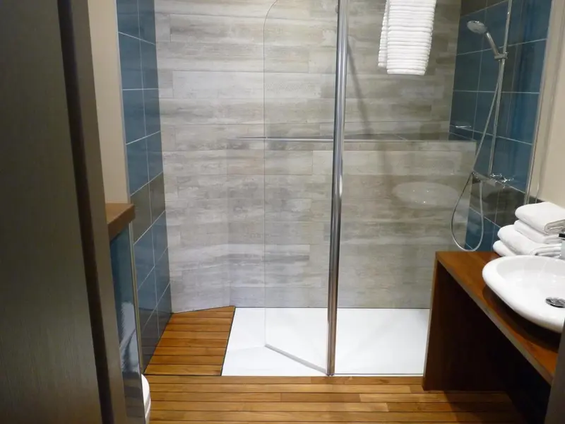 Une douche à l'italienne moderne avec des carreaux gris et un plancher en bois.
