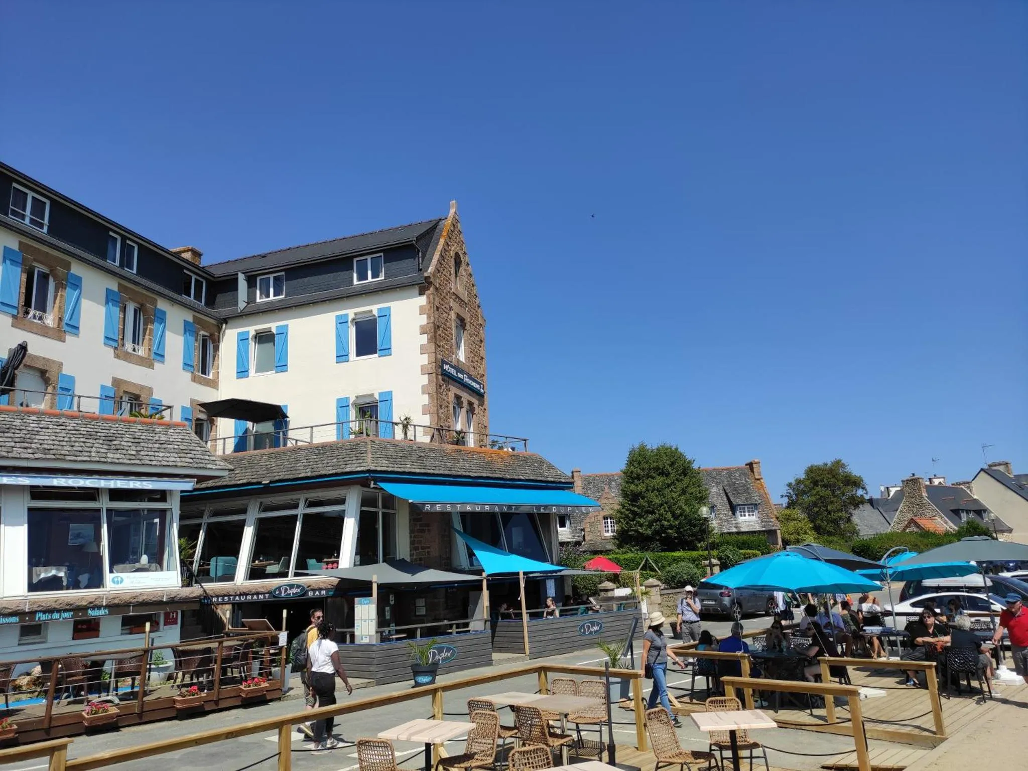 Terrasse de restaurant avec tables et parasols en bord de mer.