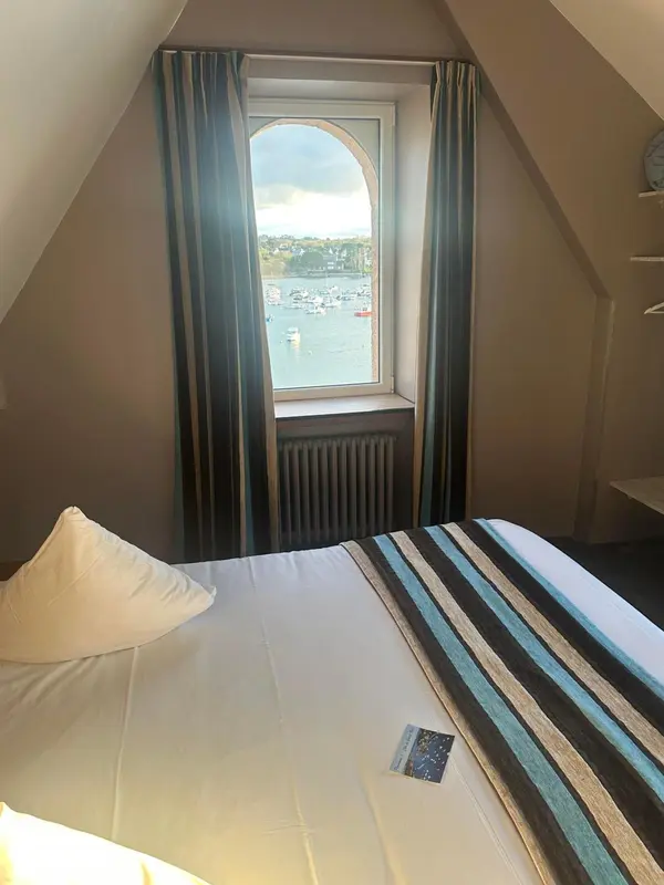 Une chambre lumineuse avec un lit et une vue sur un port.