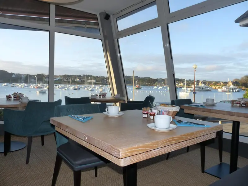 Une salle lumineuse donne sur un port de plaisance avec des bateaux amarrés.