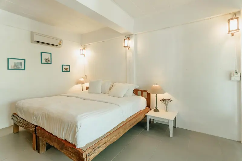 Une chambre lumineuse avec un lit recouvert de draps blancs et des tableaux décoratifs.