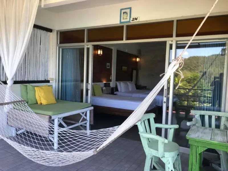Espace de détente avec hamac et mobilier de jardin donnant sur une chambre.