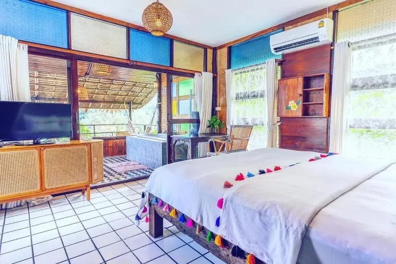 Chambre lumineuse avec un lit décoré de fleurs et un accès à une terrasse.