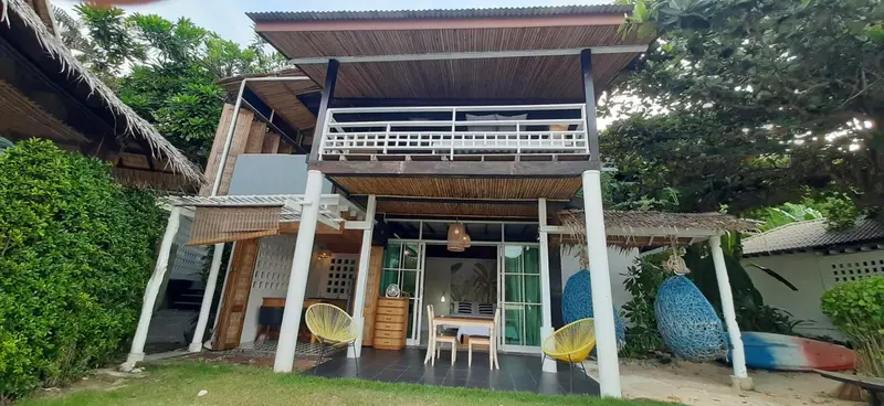 Terrasse ombragée avec mobilier de jardin devant une habitation en bois.
