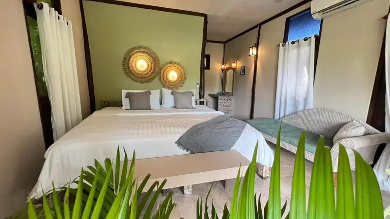 Une chambre lumineuse avec un grand lit et un coin salon.
