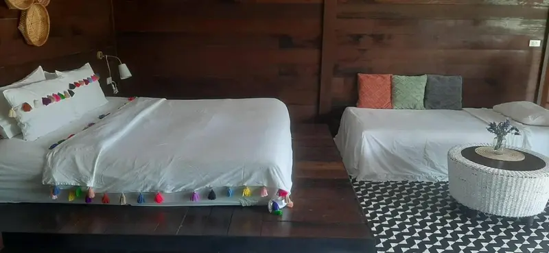 Une chambre lumineuse avec deux lits blancs et une décoration colorée.
