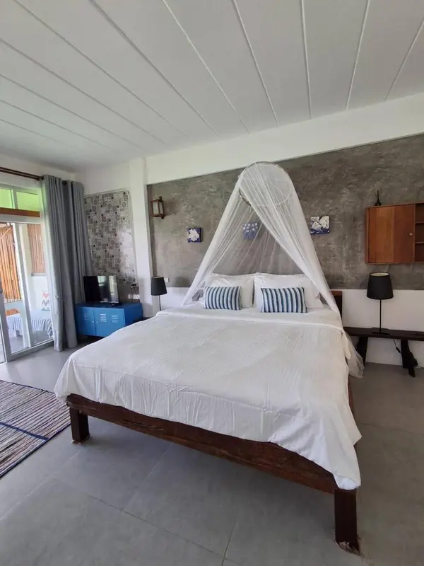 Une chambre lumineuse avec un grand lit à baldaquin et un décor sobre.