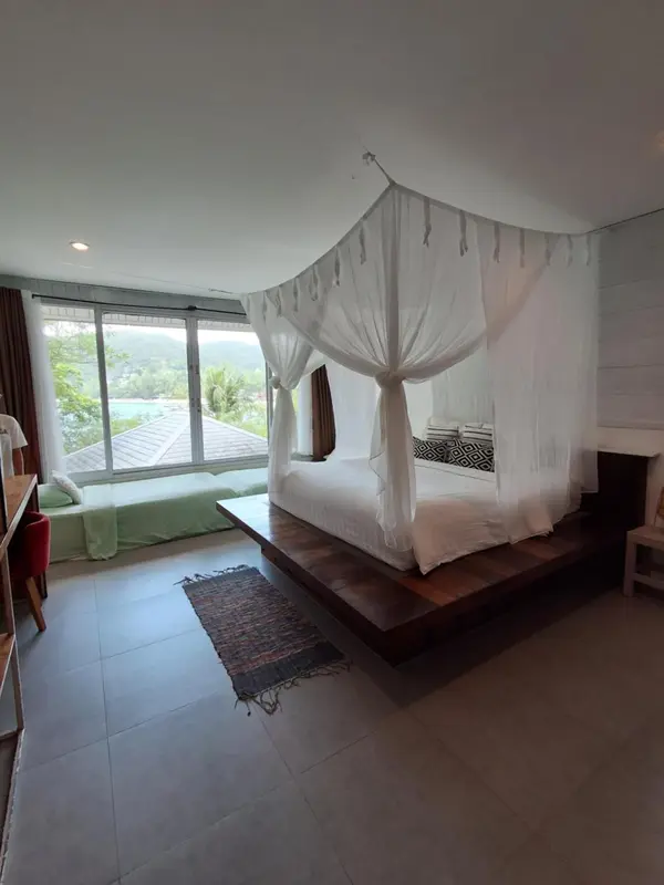 Une chambre lumineuse avec un lit à baldaquin et une vue sur la végétation.