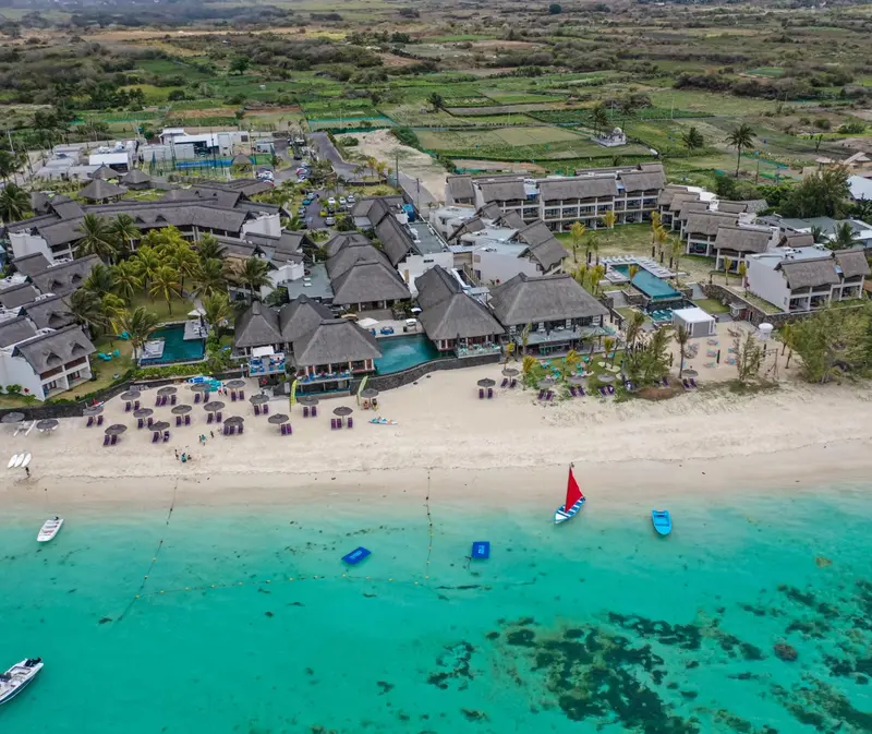 Vue aérienne d'un complexe hôtelier bordant une plage de sable fin et une mer turquoise.