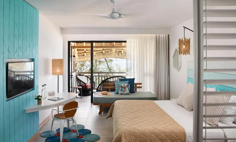 Une chambre lumineuse s'ouvre sur une terrasse avec salon de jardin.