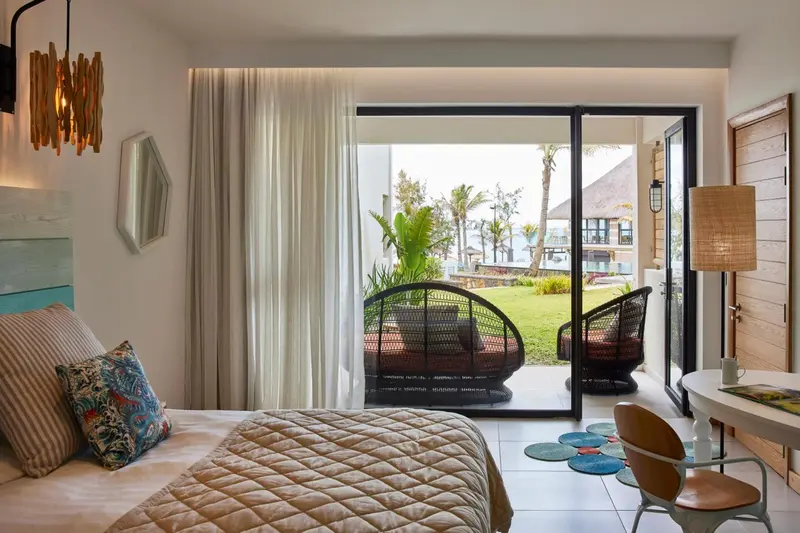 Une chambre lumineuse s'ouvre sur une terrasse avec vue sur la végétation tropicale.