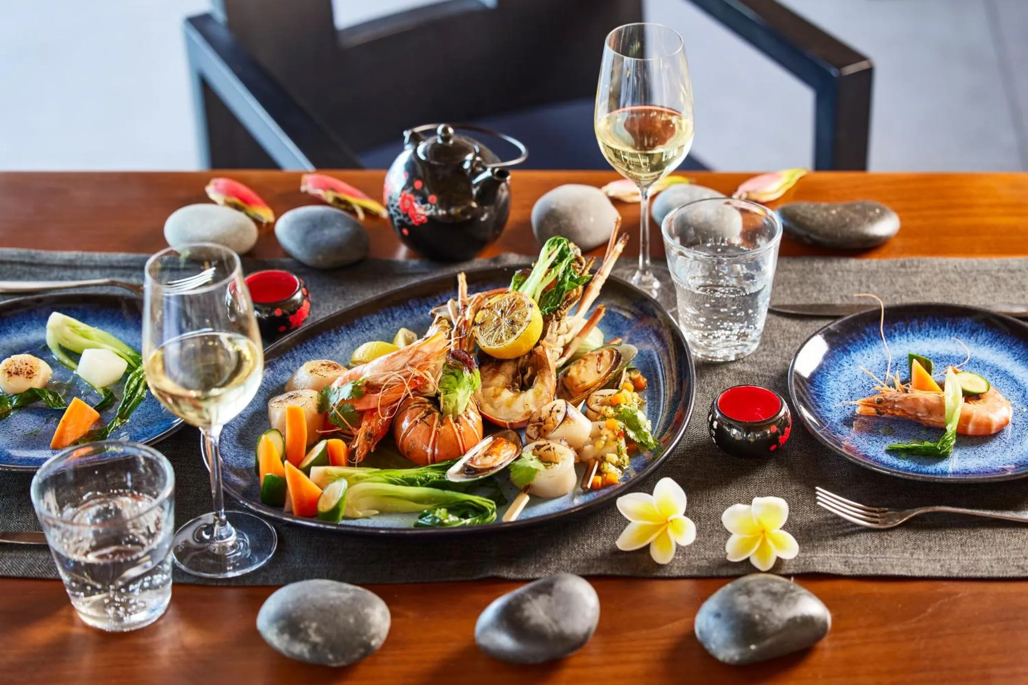 Une table dressée présente des plats de fruits de mer décorés de fleurs et de légumes.