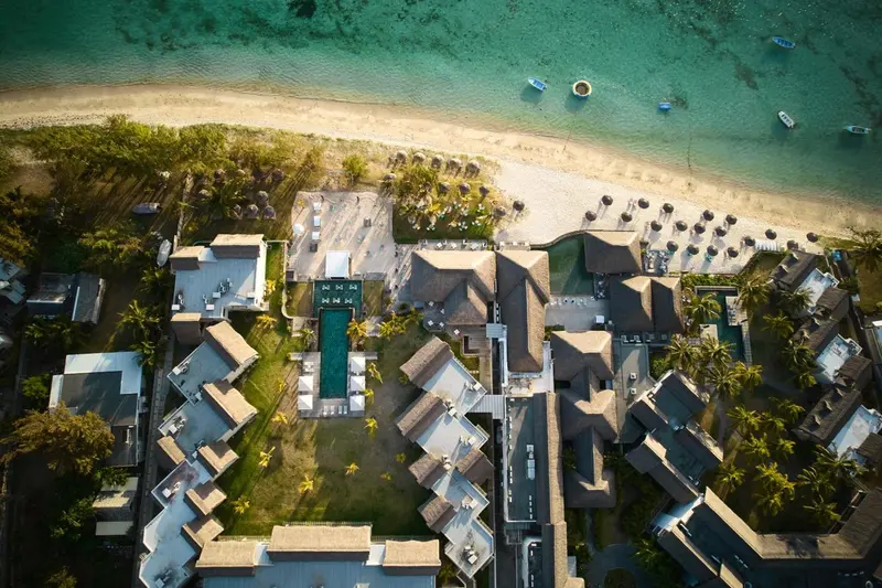 Vue aérienne d'un complexe hôtelier bordant une plage de sable fin et une mer turquoise.