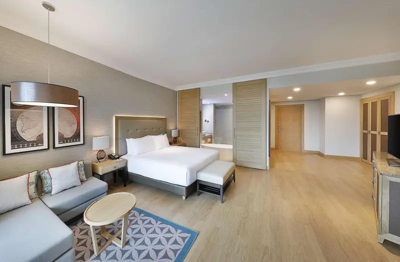 Chambre lumineuse avec un grand lit et un coin salon.