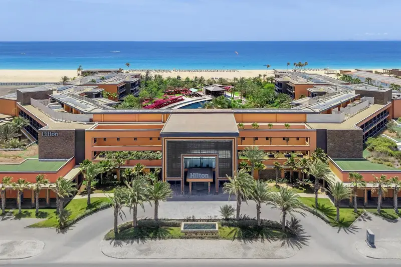 Vue aérienne d'un complexe hôtelier avec piscine et végétation tropicale.