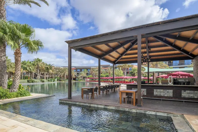 Un espace bar extérieur surplombe une piscine calme.