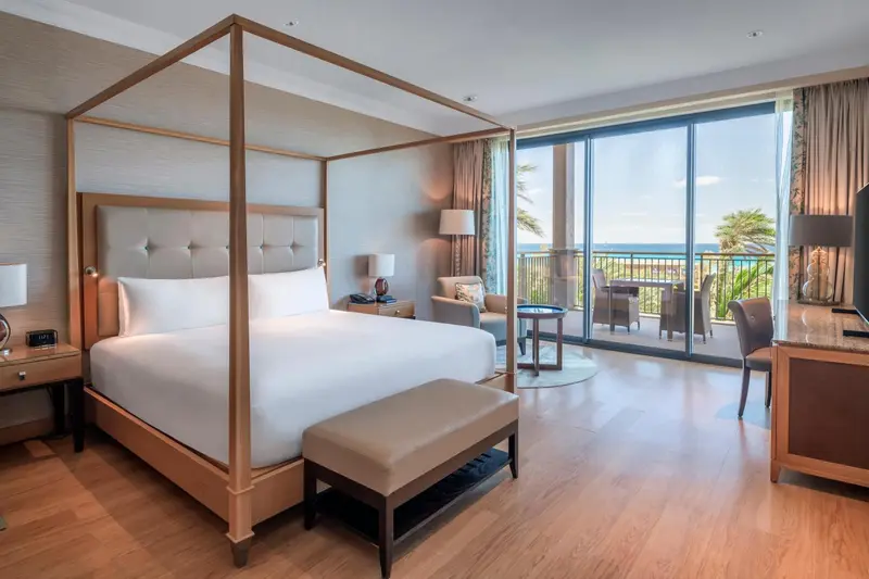 Une chambre lumineuse avec un grand lit à baldaquin et une vue sur la mer.
