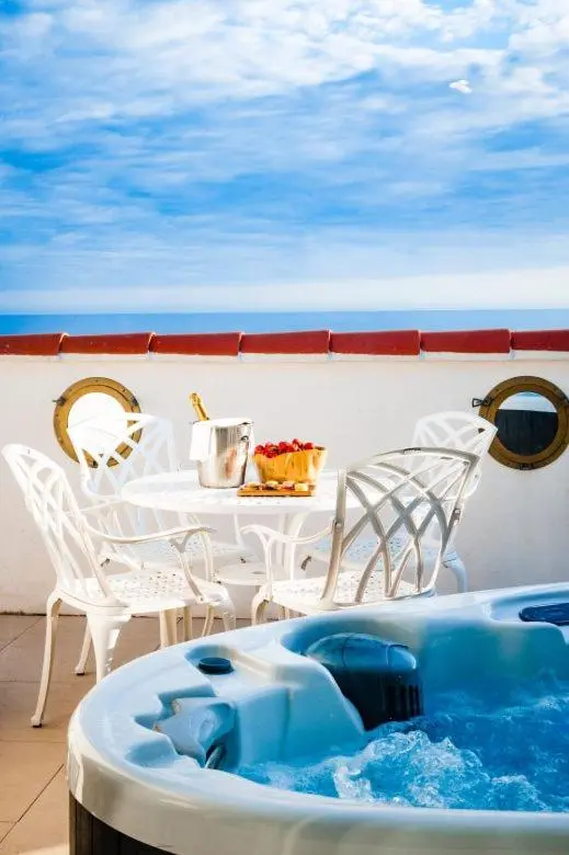 Terrasse avec jacuzzi et table à manger en extérieur.