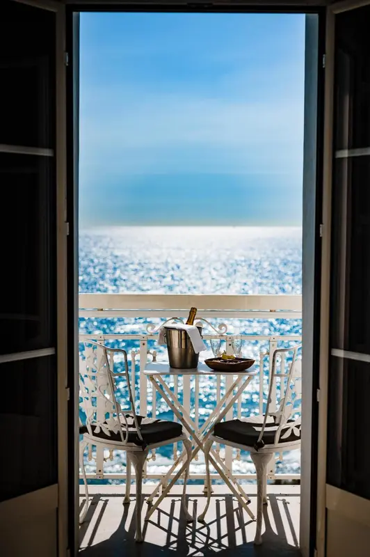 Vue dégagée sur la mer depuis une terrasse avec table et chaises.