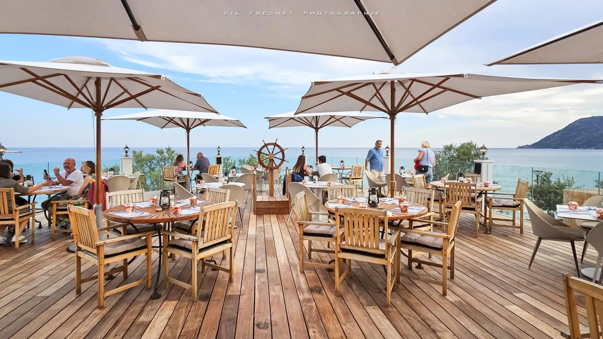 Terrasse de restaurant avec vue sur la mer et des parasols.