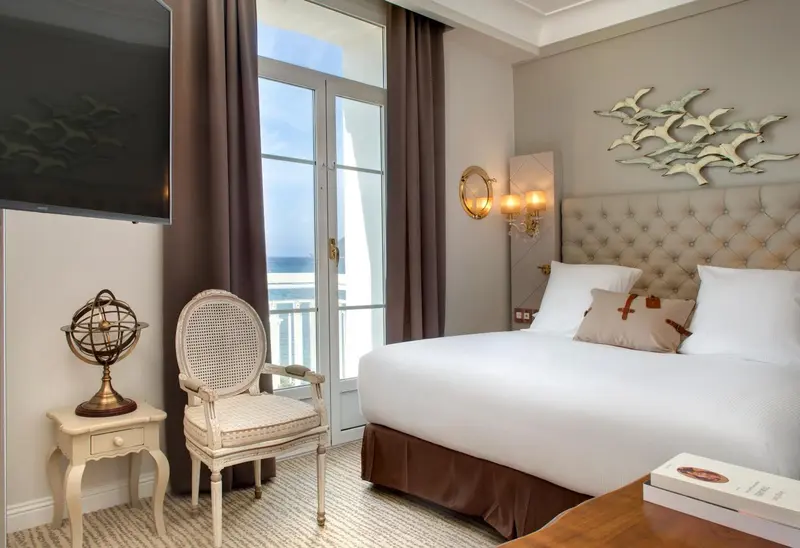 Chambre lumineuse avec un lit confortable et une vue sur la mer.