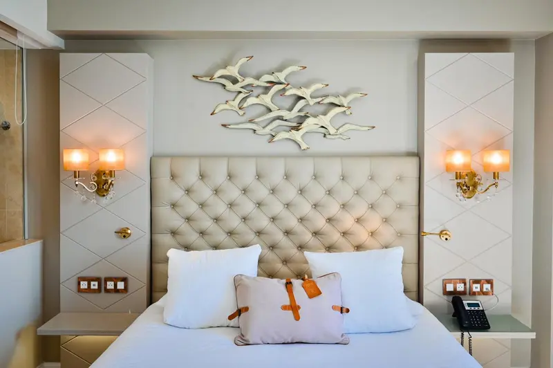 Une chambre avec un grand lit recouvert d'oreillers et d'une décoration murale en forme d'oiseaux.