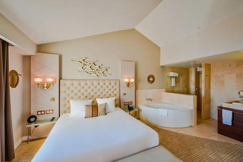 Une chambre lumineuse avec un grand lit et une baignoire.