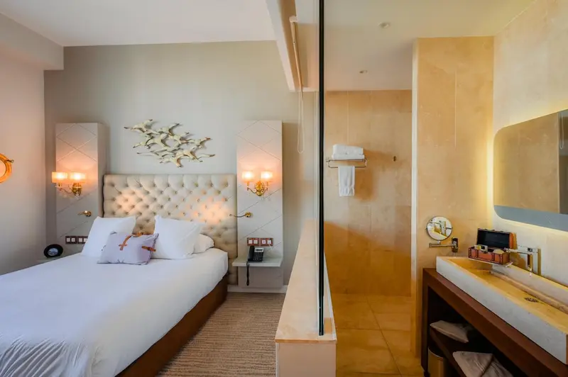 Une chambre lumineuse avec un grand lit et une salle de bain ouverte.