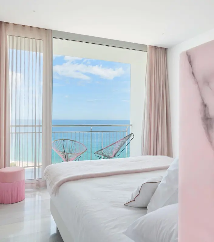 Une chambre lumineuse avec vue sur la mer depuis un balcon.