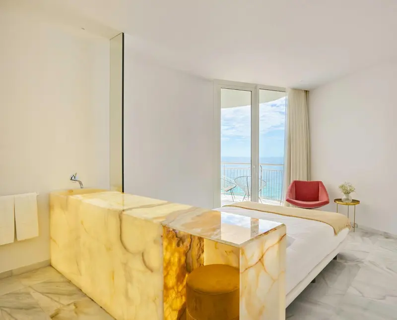Une chambre lumineuse avec baignoire et vue sur la mer.