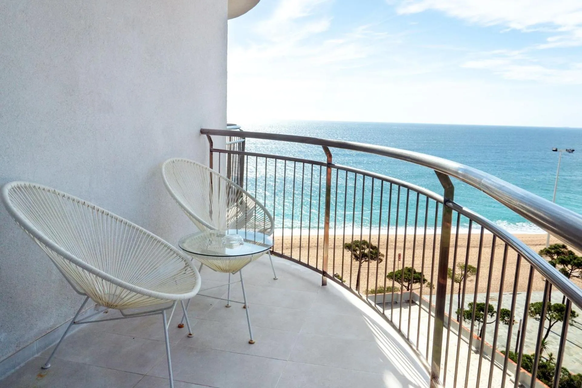 Deux fauteuils en osier sur un balcon avec vue sur la mer et la plage.
