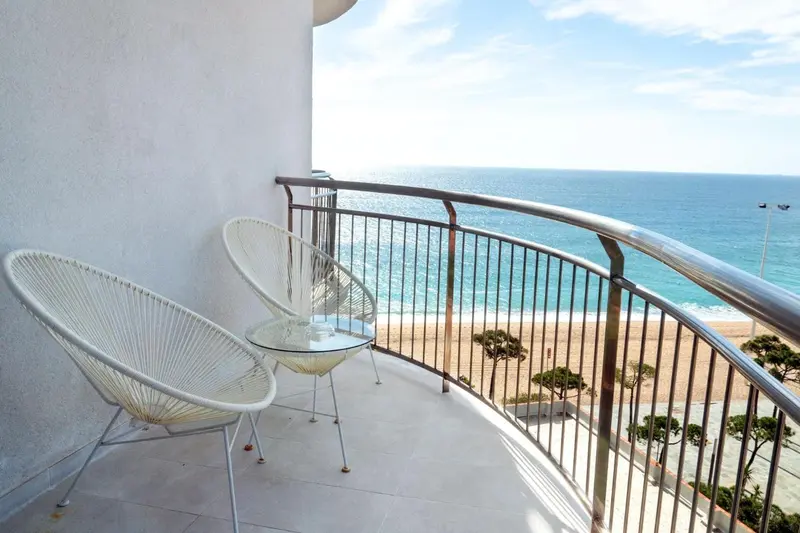 Deux fauteuils en osier sur un balcon avec vue sur la mer et la plage.