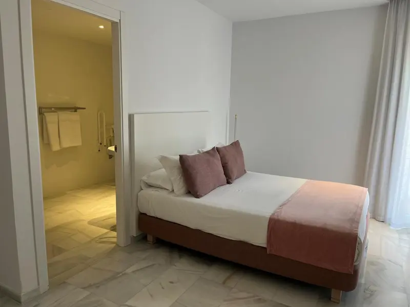 Une chambre lumineuse avec un grand lit et un accès à une salle de bain.