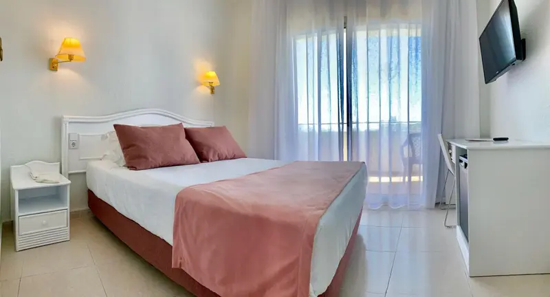 Une chambre lumineuse avec un grand lit et un accès à une terrasse.