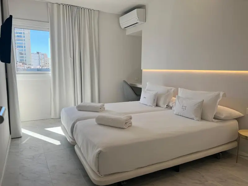 Une chambre lumineuse avec un grand lit et une fenêtre donnant sur la ville.