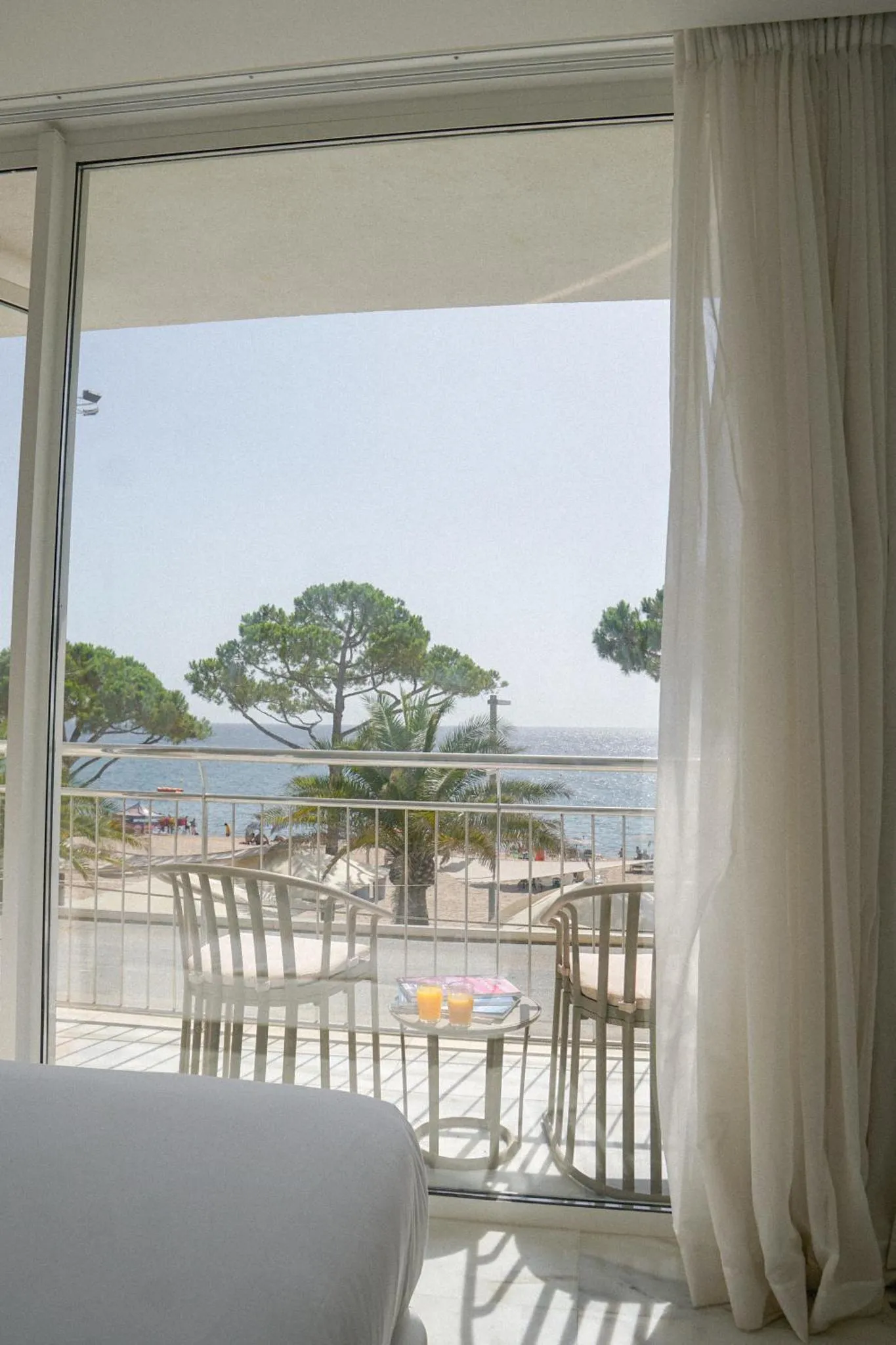 Vue sur la mer depuis une terrasse ensoleillée avec des fauteuils et une table basse.