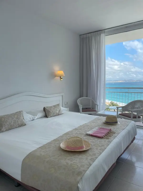 Chambre lumineuse avec un grand lit donnant sur une vue mer.