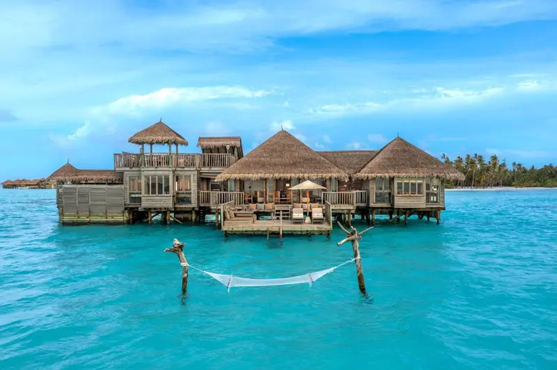 Plusieurs bungalows sur pilotis au-dessus d'une eau turquoise.
