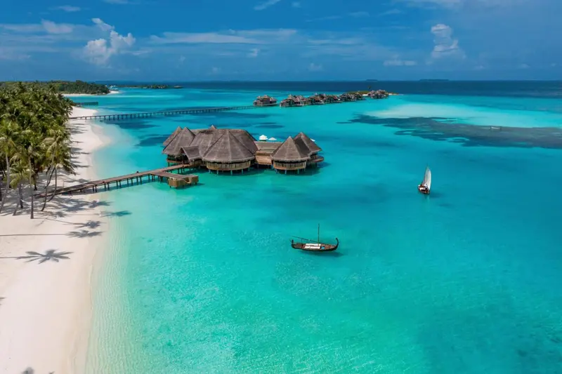 Vue aérienne d'un complexe hôtelier sur pilotis dans une eau turquoise.