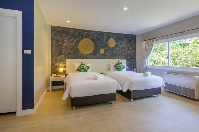 Chambre lumineuse avec deux lits simples et décoration murale.
