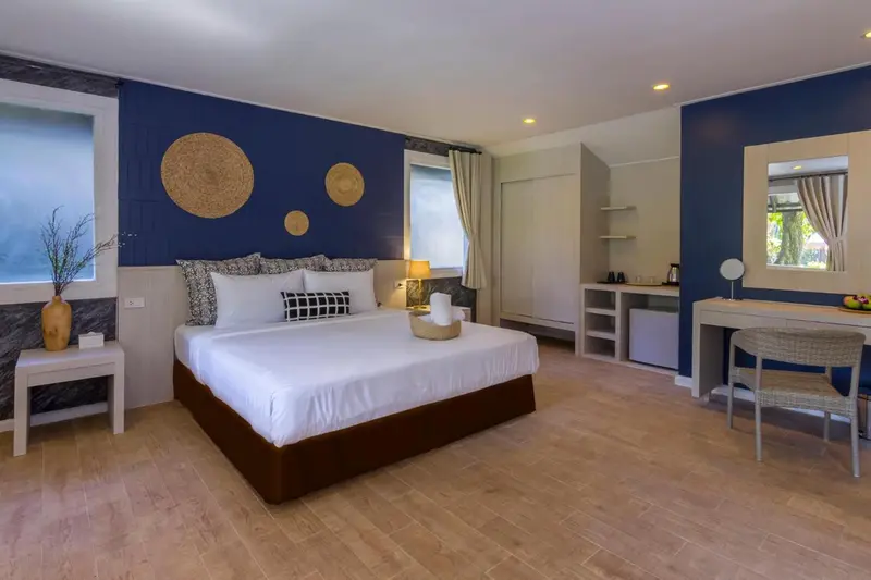Une chambre lumineuse avec un grand lit recouvert de blanc et des éléments décoratifs muraux.