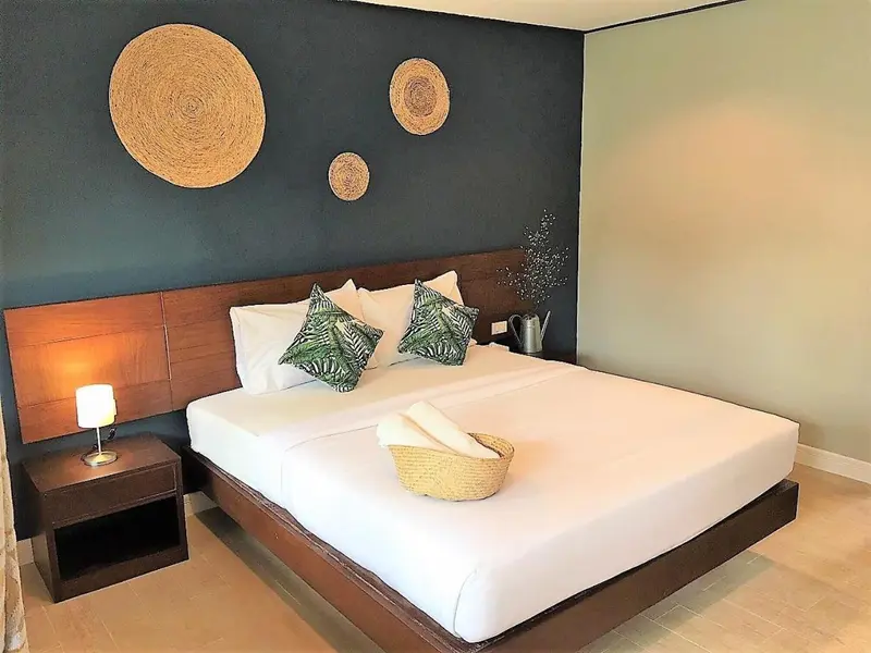 Une chambre lumineuse avec un grand lit recouvert de linge blanc et des décorations murales en fibres naturelles.
