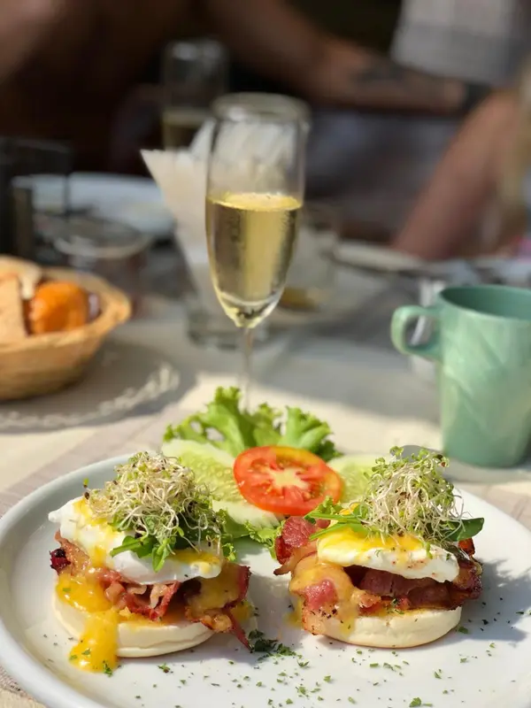 Assiette de brunch avec œufs pochés, bacon et salade.