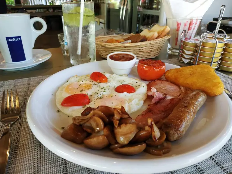 Un copieux petit-déjeuner est présenté sur une table avec des œufs, du bacon, des saucisses et des champignons.
