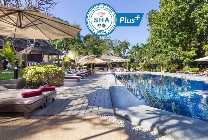 Transats alignés au bord d'une piscine turquoise dans un cadre tropical.