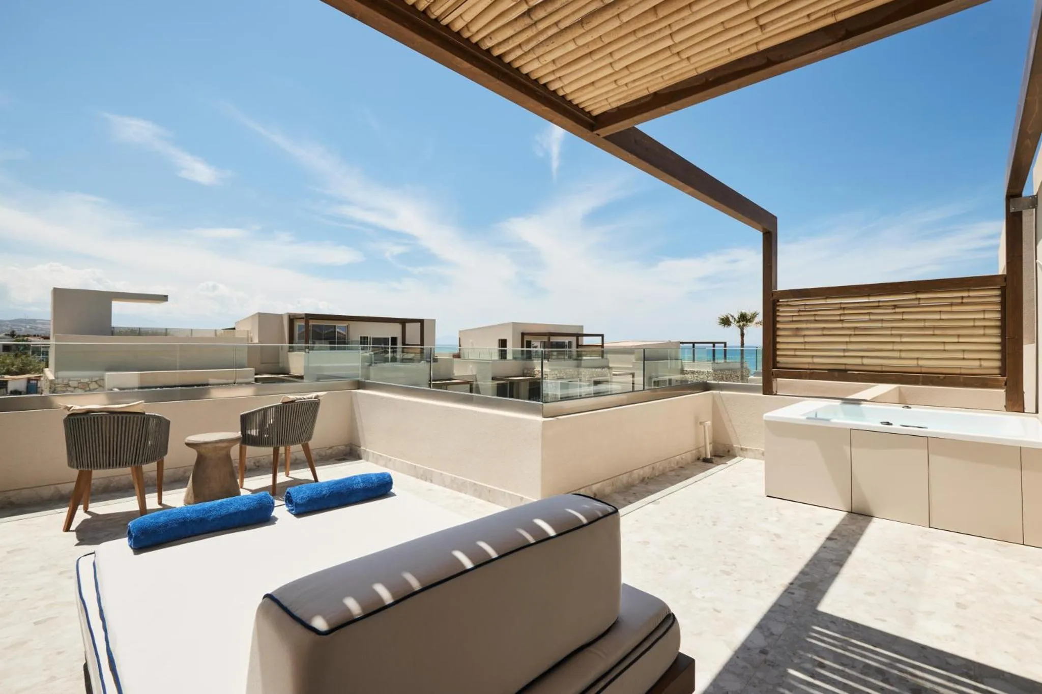 Terrasse aménagée avec transats et jacuzzi offrant une vue sur la mer.