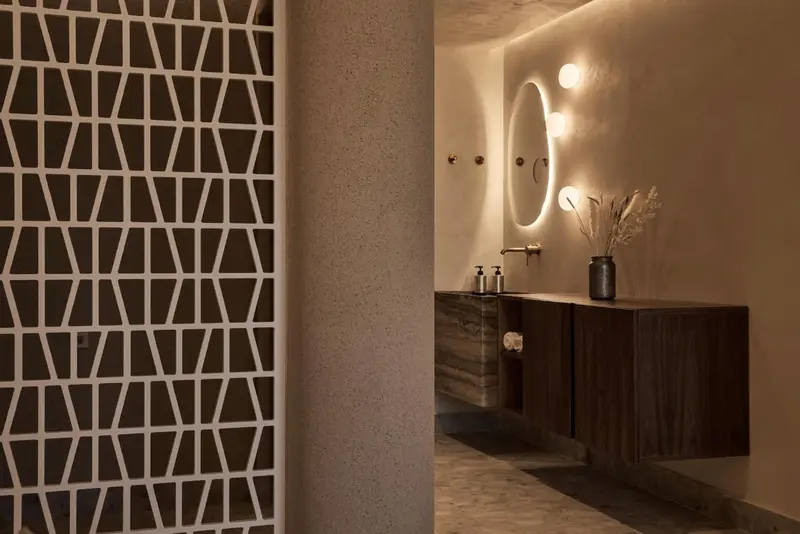 Une salle de bain moderne avec un lavabo en pierre et un mur décoratif ajouré.